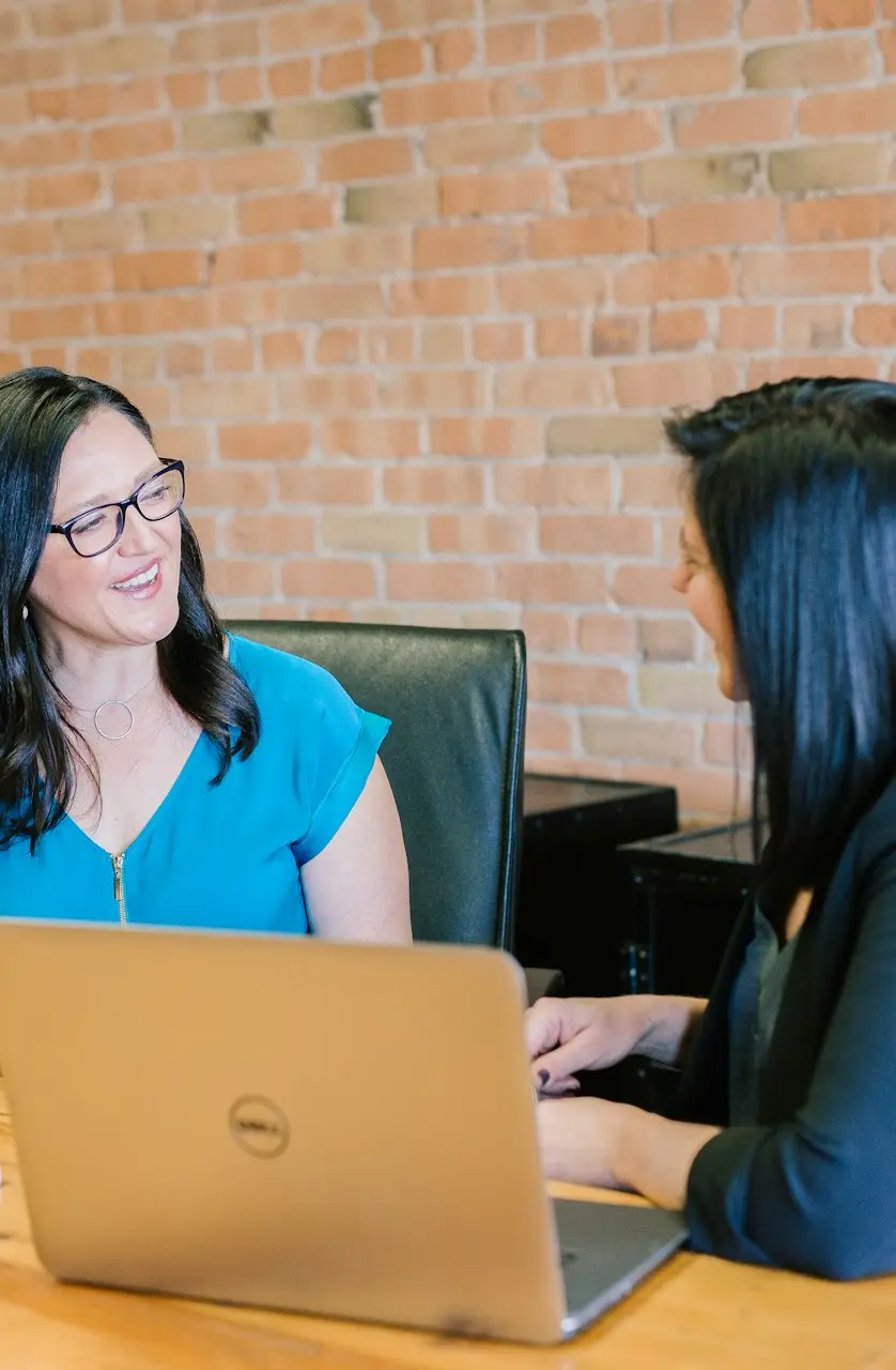 woman in teal t-shirt sitting beside woman in suit jacket